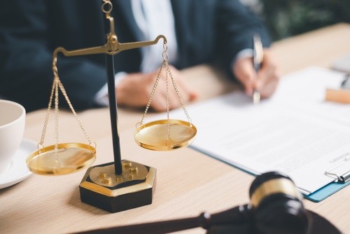 scales of justice and gavel on desk with attorney signing legal documents